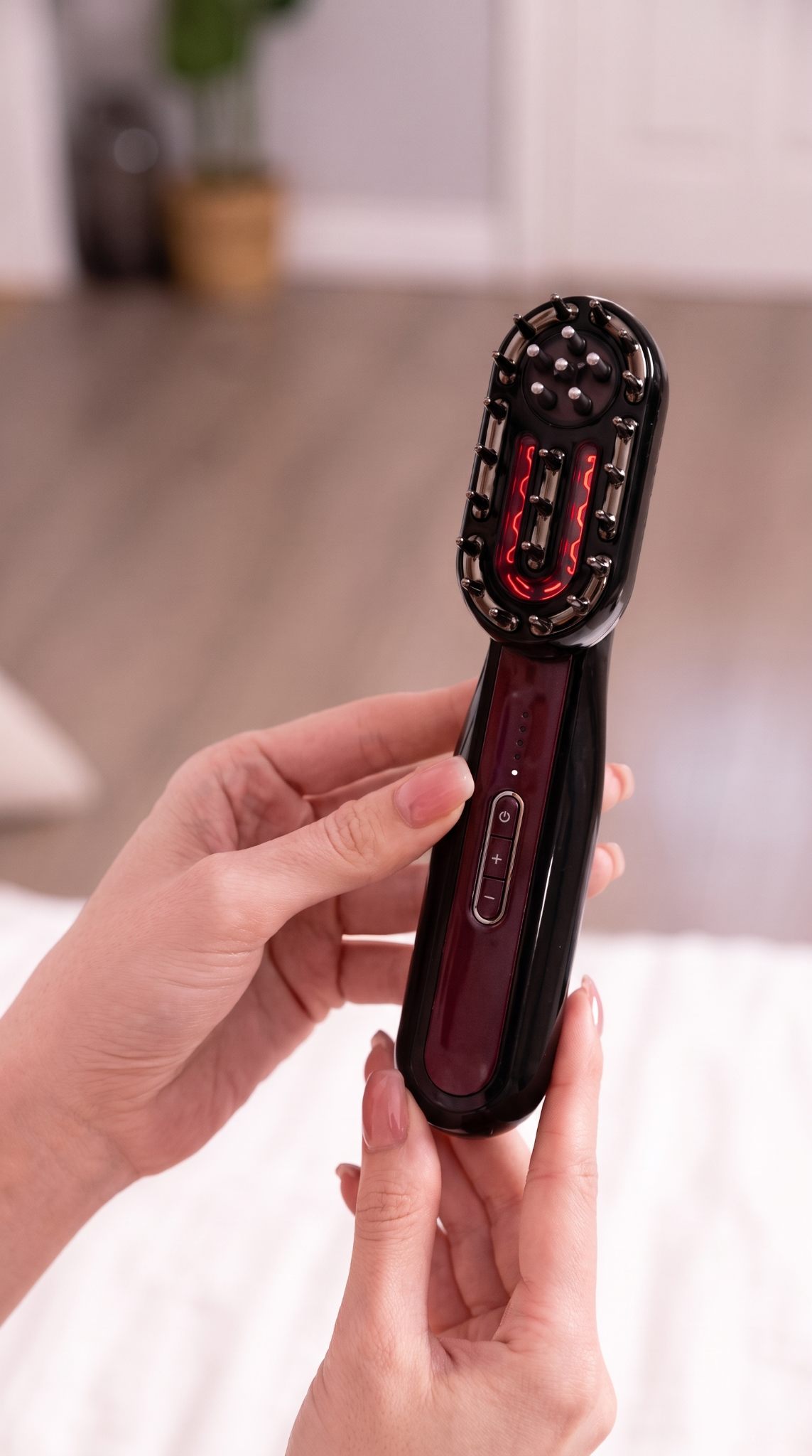 Céliane beauty massager held in two hands with the scalp attachment illuminated